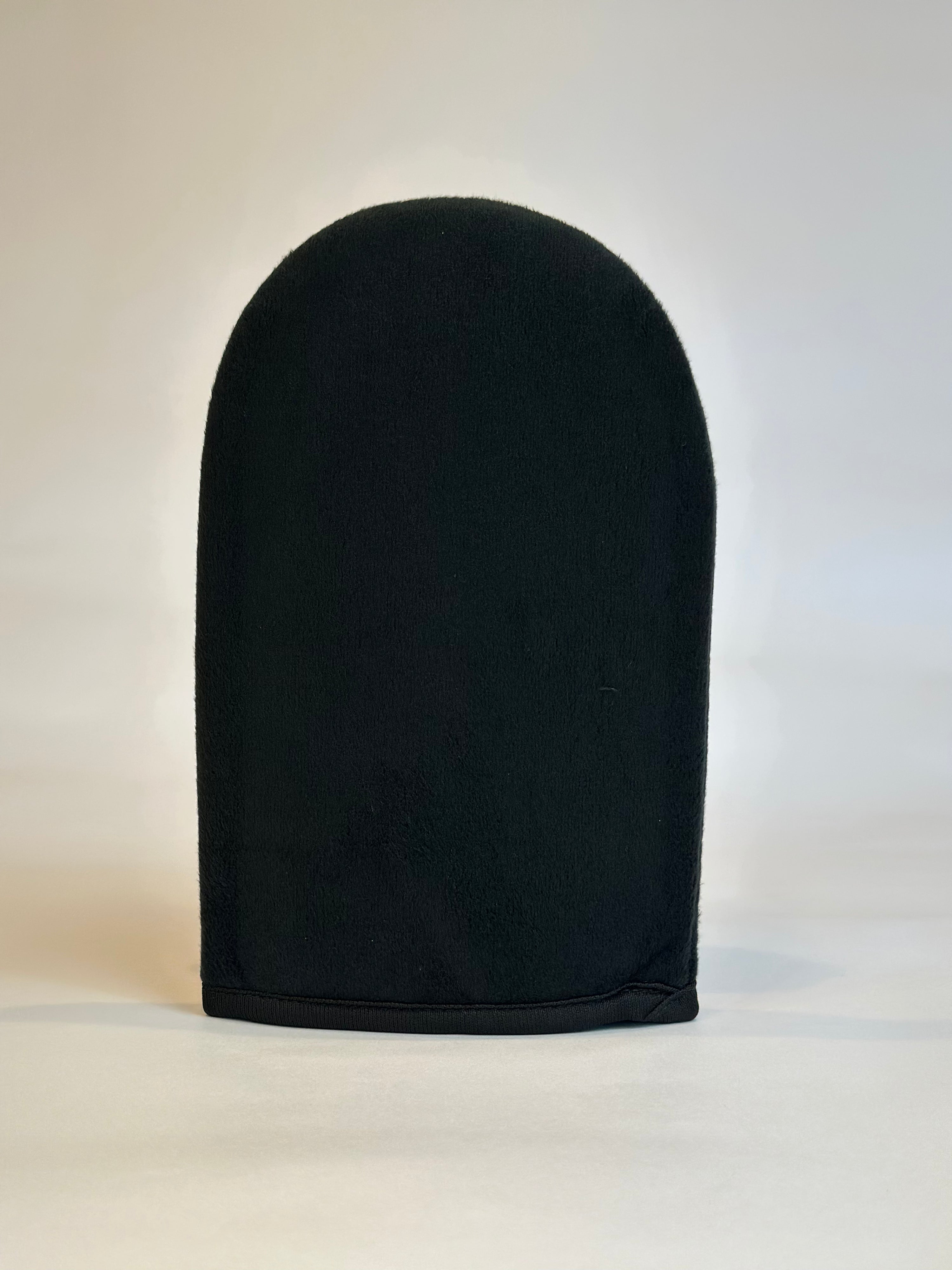 A black velvety applicator mitt for self-tan application