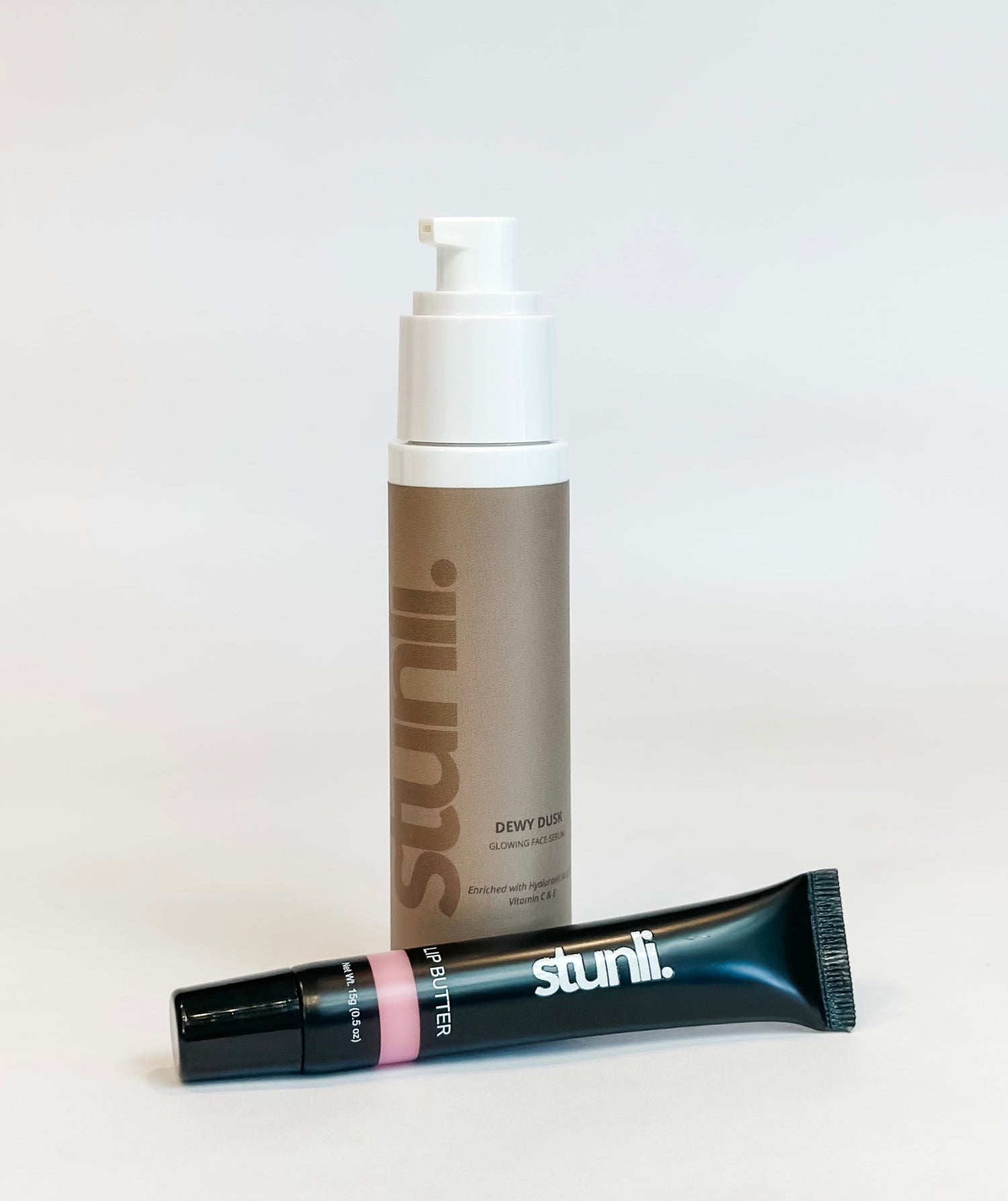 A bottle of Stunli Dewy Dusk Hydrating Serum and a tube of Stunli Vegan Lip Butter, both with the brand name visible.