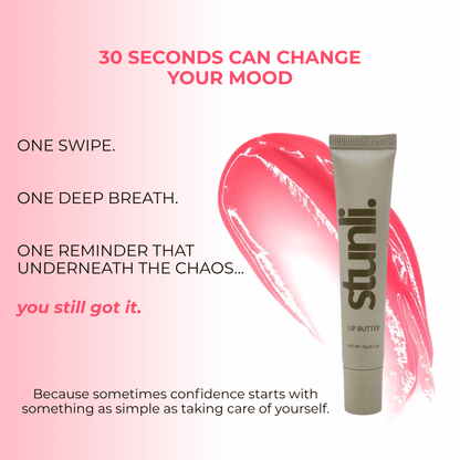 A lip butter tube stands on a white background with a pink lipstick smear behind it. The tube is light gray with dark brown text reading &
