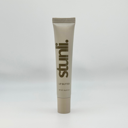 A single tube of Stunli lip butter in a warm taupe-beige color, standing upright against a light gray studio background.