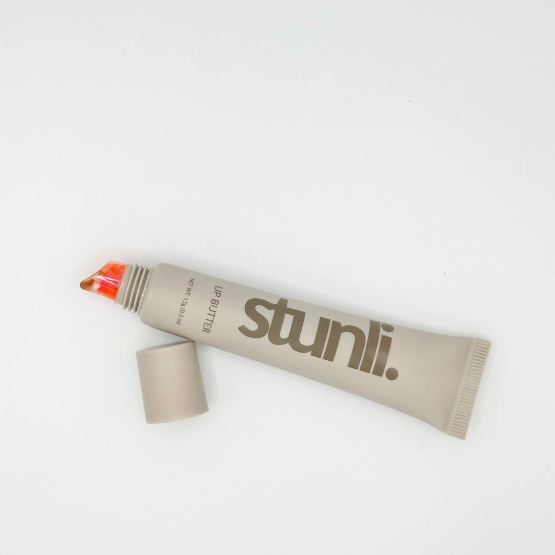 A squeeze tube of Stunli lip butter in a warm taupe-beige color with the brand name printed in dark brown.