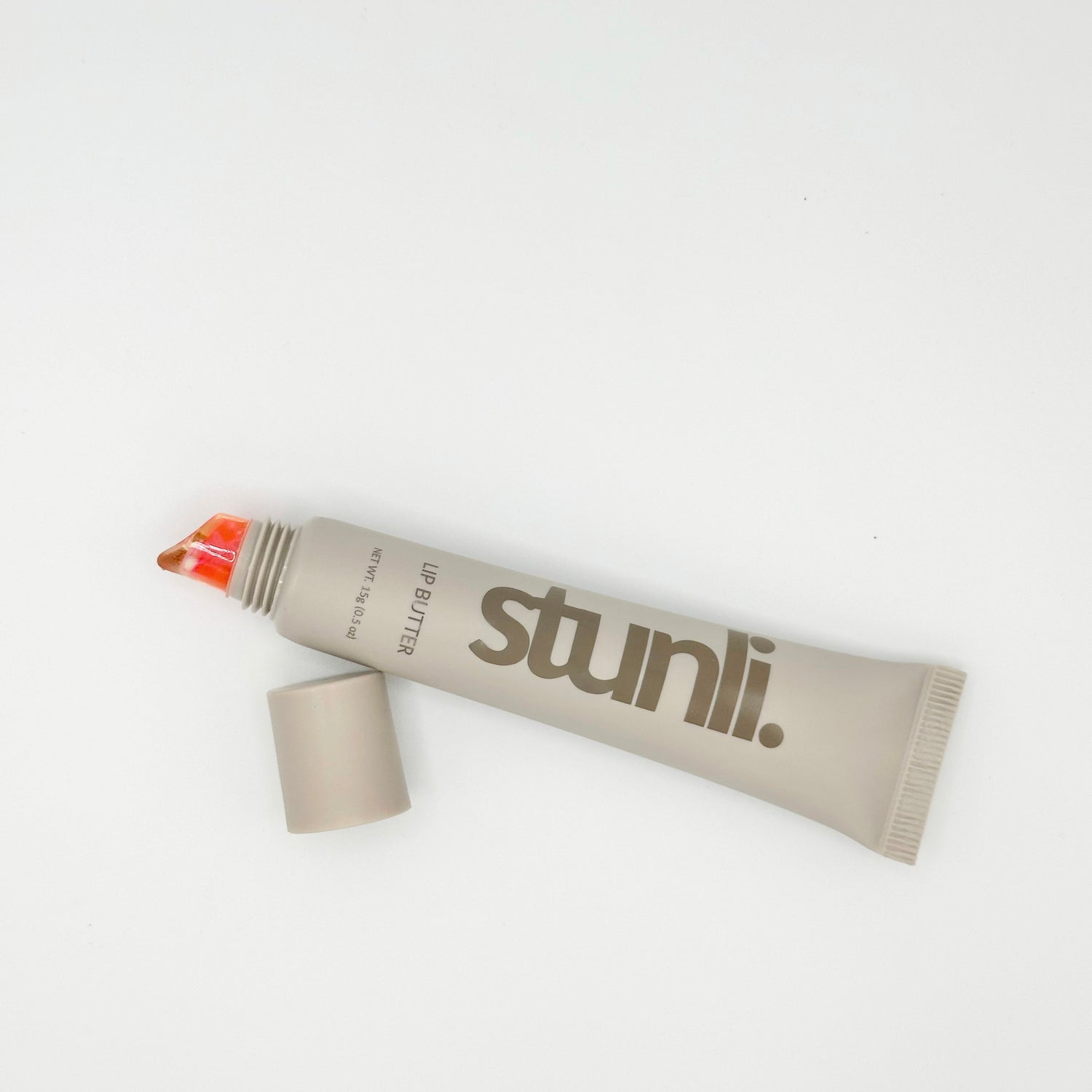 A squeeze tube of Stunli lip butter in a warm taupe-beige color with the brand name printed in dark brown.