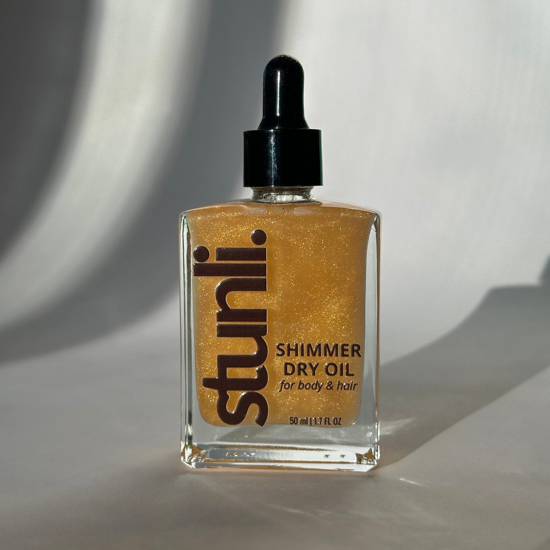 Bottle of Stunli Shimmer Dry Oil on a light background