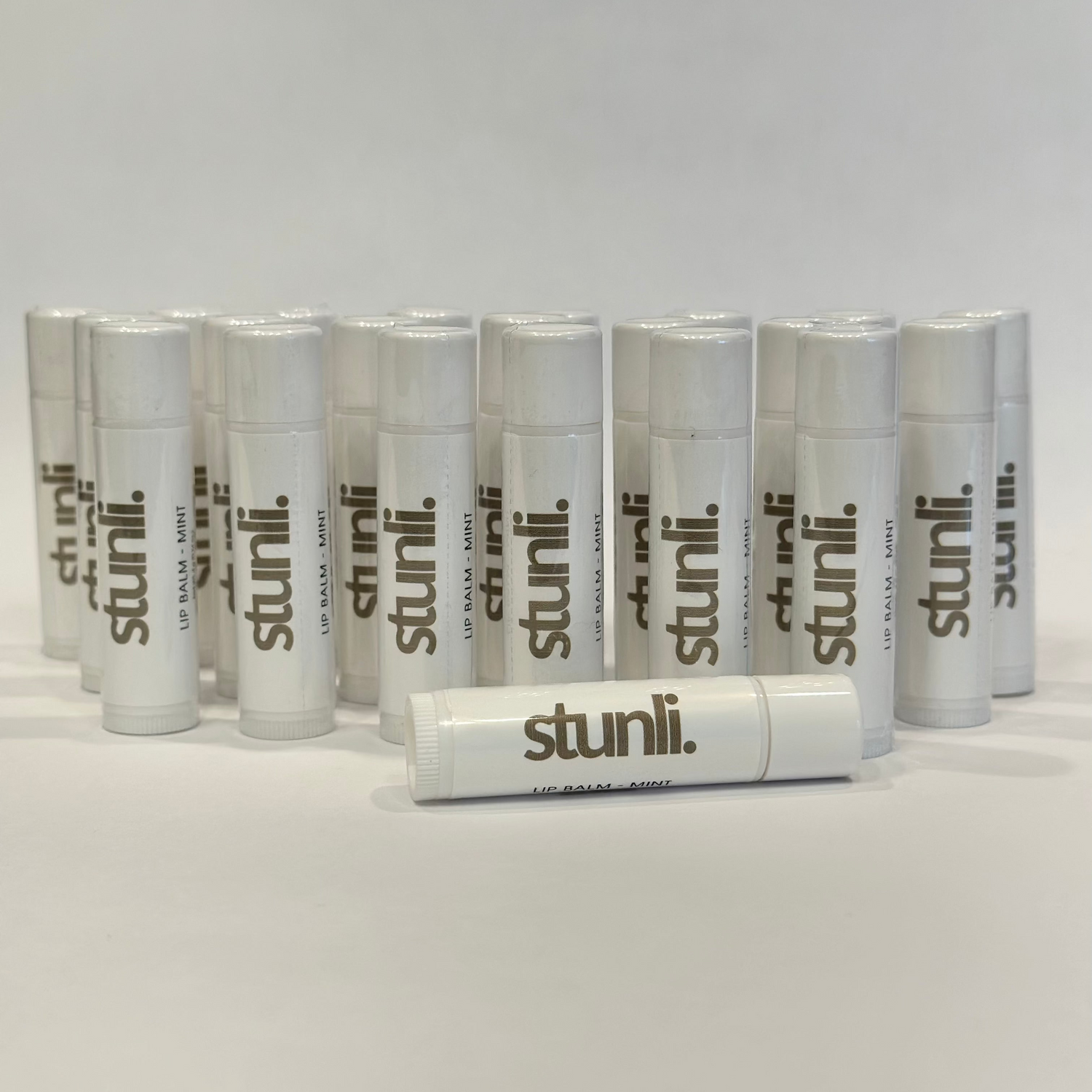 Multiple stunli lip balms arranged on a light gray background